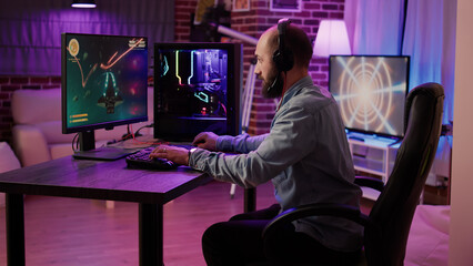 Gamer playing fast paced space shooter simulation screaming victorious at the computer screen after winning difficult level. Caucasian man celebrating victory in internet multiplayer action game.