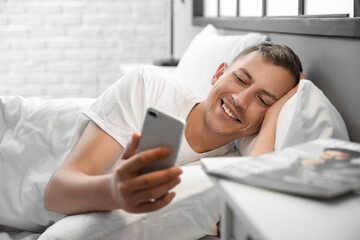 Young man using mobile phone at home in morning