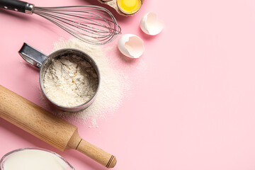 Mug with flour, whisk and rolling pin on pink background