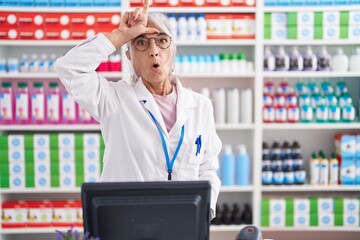 Middle age woman with tattoos working at pharmacy drugstore making fun of people with fingers on...