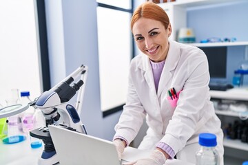 Young caucasian woman scientist using laptop working at laboratory