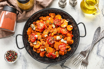 Frying pan with tasty baked vegetables and spices on light background