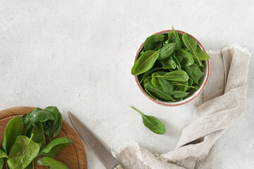 Fresh spinach leaves with water drops in ceramic bowl and cutting desk on the light background....