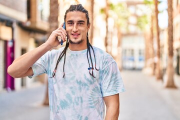 Young man smiling confident talking on the smartphone at street