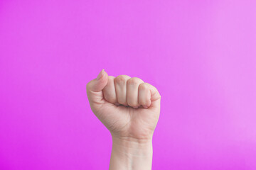 Female fist on a pink background. The concept of feminism and the struggle for women's rights.