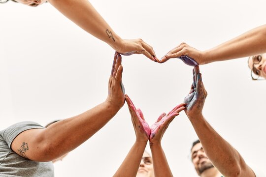 Group of people doing heart sign with hands together at art studio.