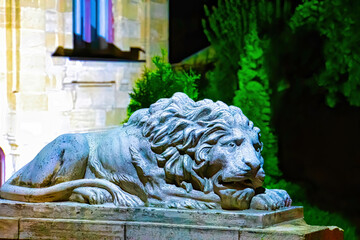 A lion statue sits majesticaly on it's pedestal in the park