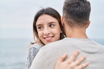 Man and woman couple smiling confident hugging each other at seaside