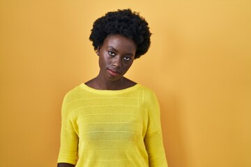 Fototapeta premium African young woman standing over yellow studio looking sleepy and tired, exhausted for fatigue and hangover, lazy eyes in the morning.