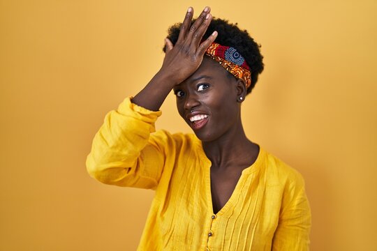 African young woman wearing african turban surprised with hand on head for mistake, remember error. forgot, bad memory concept.