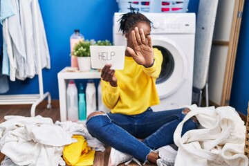 Beautiful black woman doing laundry asking for help with open hand doing stop sign with serious and confident expression, defense gesture