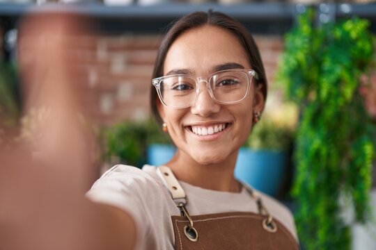 Young beautiful hispanic woman florist smiling confident make selfie by camera at florist