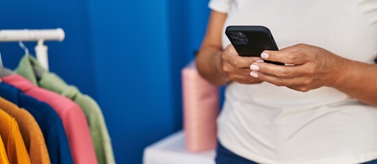 Middle age hispanic woman using smartphone waiting for washing machine at laundry room