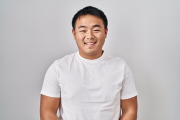 Obraz premium Young chinese man standing over white background with a happy and cool smile on face. lucky person.