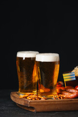 Board with glasses of beer, food and flag on table against dark background. Oktoberfest celebration