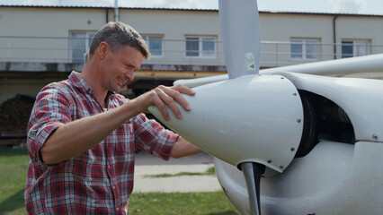 Aviator fixing airplane propeller smiling enjoying preflight process close up. - obrazy, fototapety, plakaty