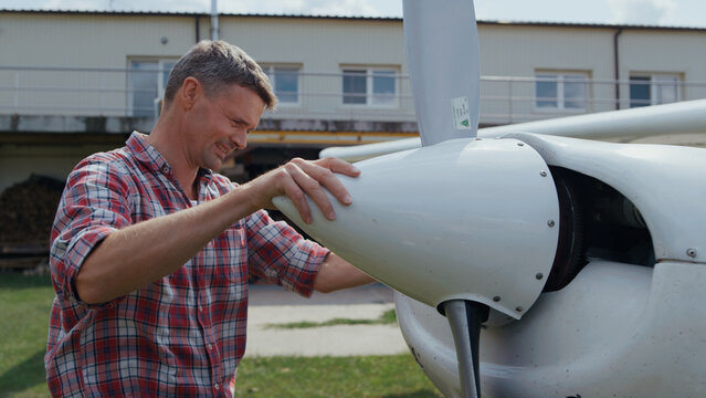 Aviator fixing airplane propeller smiling enjoying preflight process close up.
