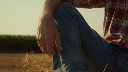 Man leg straw bale in sunlight closeup. Field worker resting on hay stack sunset © stockbusters