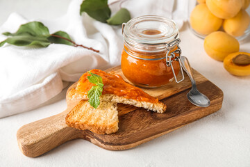 Wooden board of tasty sandwiches with apricot jam on light background