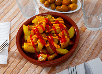 Patatas bravas, traditional Spanish potatoes snack tapa with creamy and tomato sauces