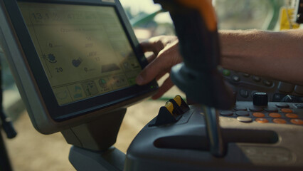 Driver hand control combine automatic system screen at countryside closeup. 