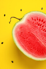 Half of tasty watermelon with seeds on yellow background