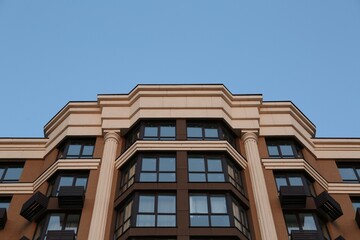 Obraz premium Facade of beautiful residential building against blue sky, low angle view
