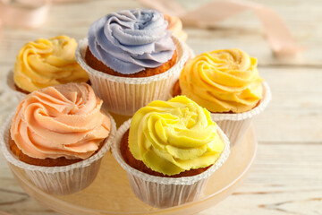 Stand with tasty cupcakes on white table, closeup