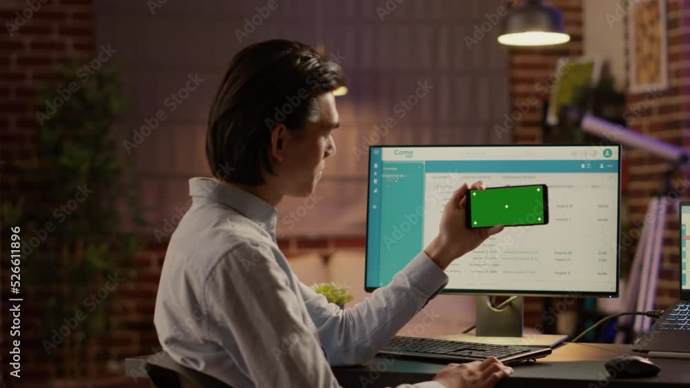 Poster businessman holding smartphone with horizontal greenscreen at desk. looking at isolated mockup backg