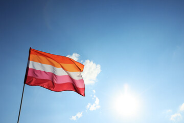 Bright lesbian flag fluttering against blue sky. Space for text