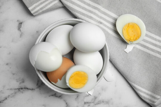 Hard boiled eggs and kitchen towel on white marble table, flat lay