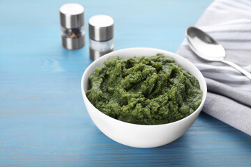 Bowl with green tasty puree on light blue wooden table