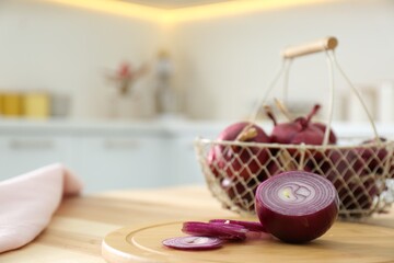 Fototapeta na wymiar Cut red onion on wooden table in kitchen