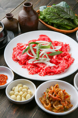 Bulgogi, a traditional Korean food on a black stone plate with a wooden background, and side dishes 나무배경에 검은 돌판위에 있는 한국 전통 음식인 불고기와 밑반찬