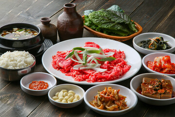 Bulgogi, a traditional Korean food on a black stone plate with a wooden background, and side dishes 나무배경에 검은 돌판위에 있는 한국 전통 음식인 불고기와 밑반찬