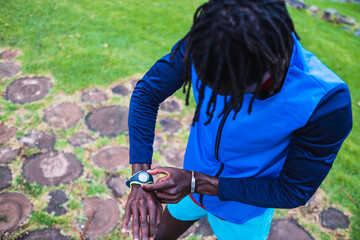 Fototapeta na wymiar Black man in sportswear manipulating his watch before starting to run.