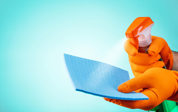 Male hahds in gloves spraying cleaning spray on sponge. concept of cleaning service.