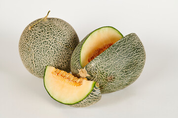 Sliced and whole cantaloupe on a white background
