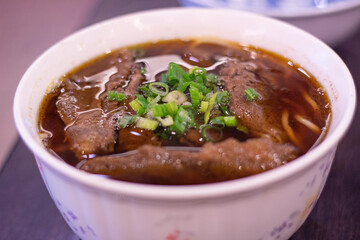 Close up of a bowl of delicious Taiwanese beef noodles with spring union topping, Taipei, Taiwan