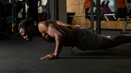 African american man doing one arm push ups in the gym. 