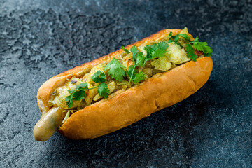 classic hot dog with ketchup and mustard and chips on dark stone table