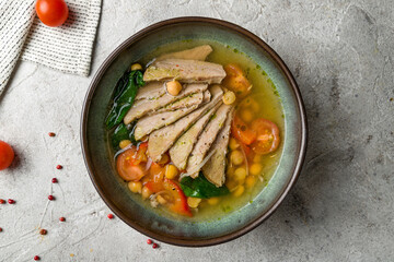 Beef broth with meat, spinach, nut and tomatoes on bowl on grey table top view