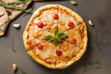 Italian pizza Margherita with cheese, tomatoes and basil on brown table top view