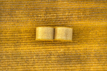 Aerial views of bales of hay in a beautiful, late summer landscape with golden hues on the ground and fluffy clouds against a blue sky above.  - 526629223