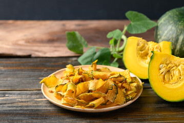 Pumpkin chips on plate with wooden background, Healthy vegan snack
