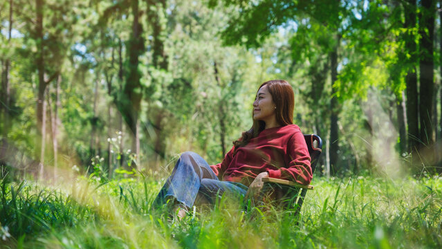 Portrait image of a beautiful young asian woman sitting and relaxing on a chair in the park