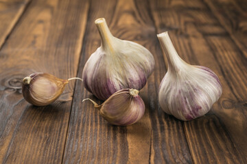 Two heads and two cloves of garlic on a wooden background.