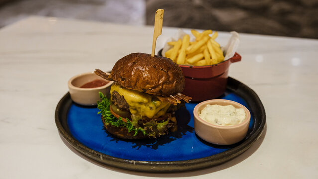 Hamburger With Brown Healthy Bread And French Fries On A Plate With Ketchup And Mayonaise