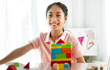 Portrait of enjoy happy asian little asian girl smiling playing with toy build wooden block board game at home