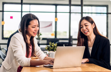Obraz premium Asian two business woman meeting analyzing and discussing strategy with startup project.Creative business people plan and brainstorm with desktop computer on conference in office.Teamwork